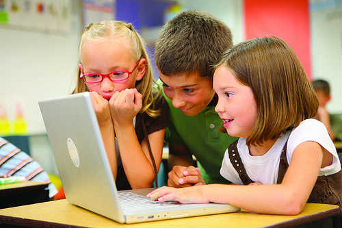 τρία παιδιά κοιτούν την οθόνη ενός υπολογιστή