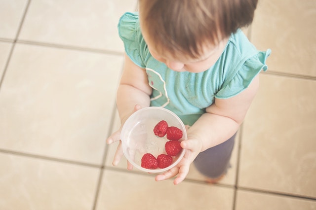 μικρό κορίτσι κρατάει ένα μπολ με φράουλες