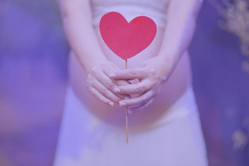 έγκυος γυναίκα που κρατά μια καρδιά